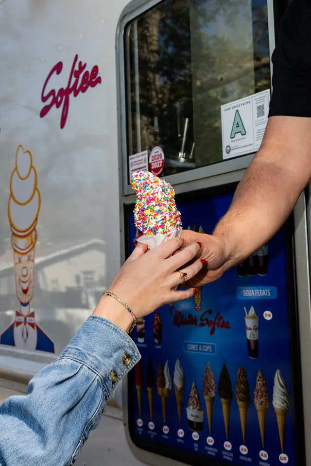 A Mister Softee Charleston employee handing over a sprinkle-covered soft serve cone at the truck window