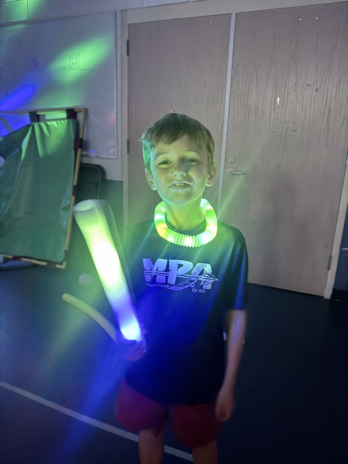 A student smiling while wearing glow bracelets at the MPA Glow Party