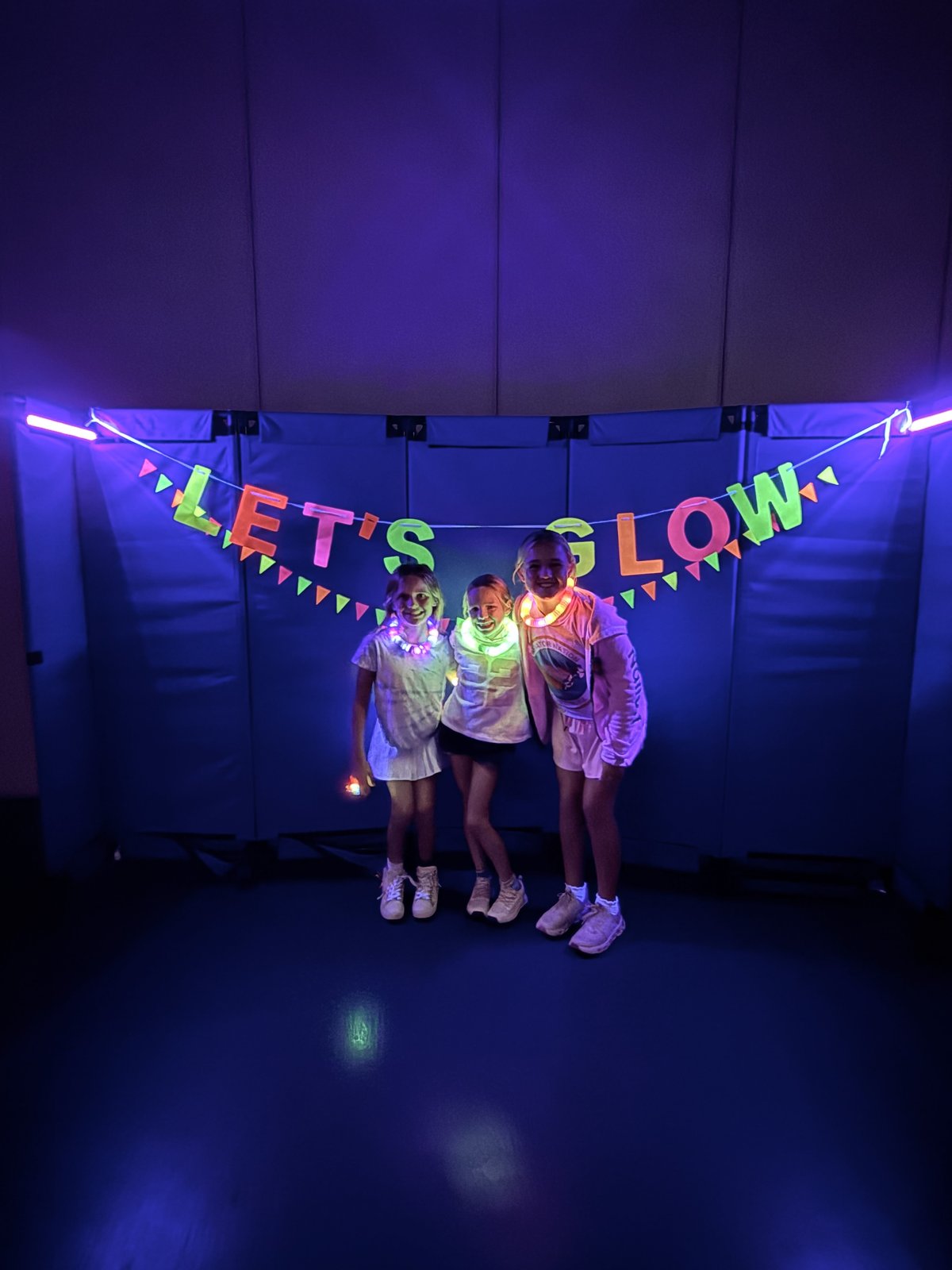 Students dancing beneath the Let's Glow banner at the MPA Glow Party