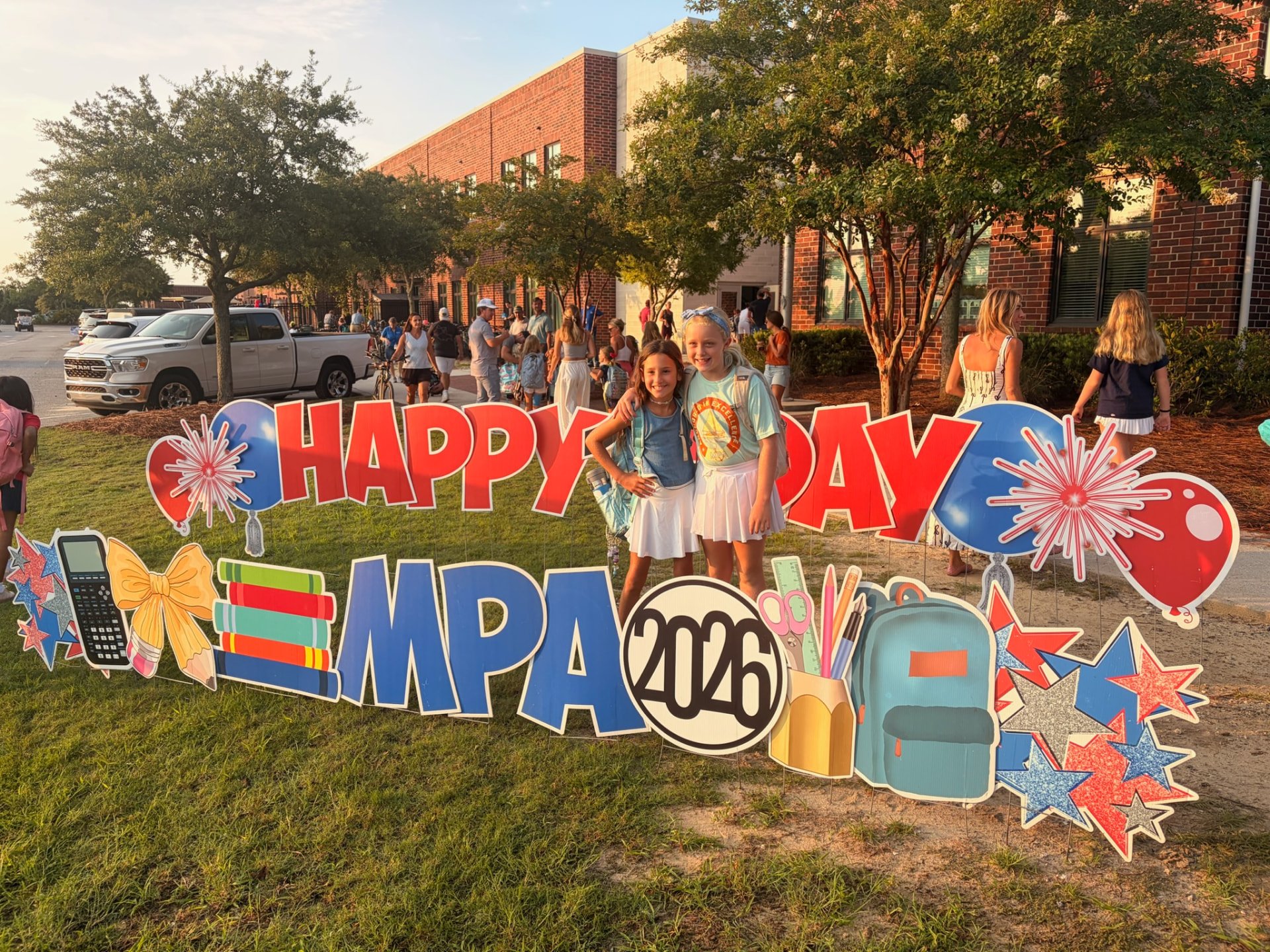 Two MPA students posing at the Happy First Day MPA 2026 sign in the morning sun